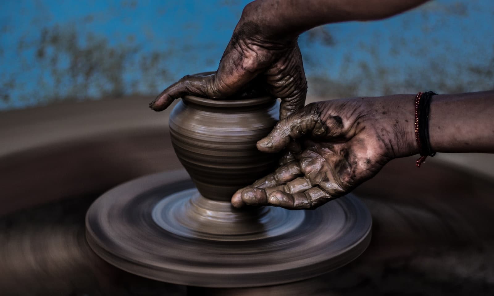 An artisan's hands shaping a clay vessel on a potter's wheel